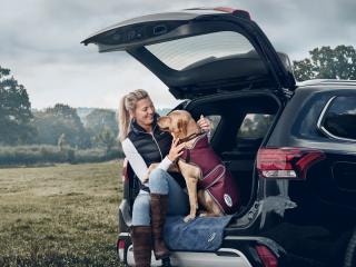 Woman sitting with dog wearing WeatherBeeta dog coat in boot of car