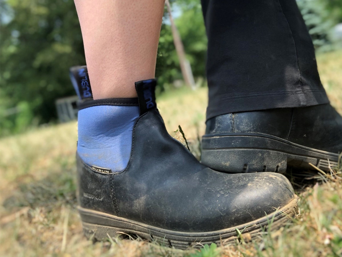 Close up of ankle boot covered in mud with bell bottom pants on the other leg