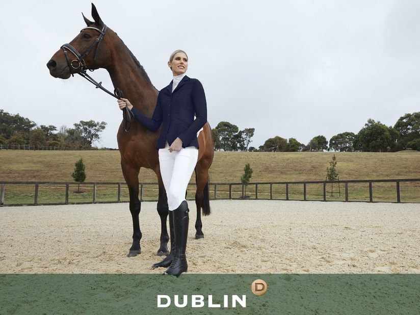 Woman wearing competition apparel standing with horse